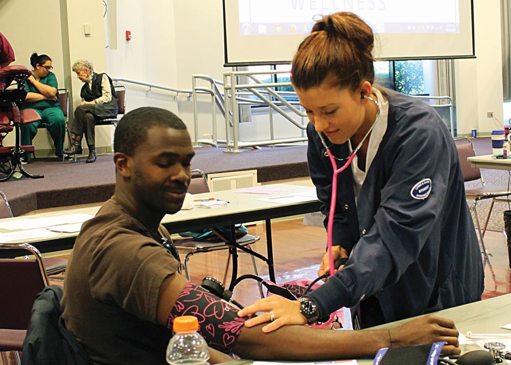 Computer Engineering major, Curtis Collins has his blood pressure measured by Nursing student, Breanna Book. 