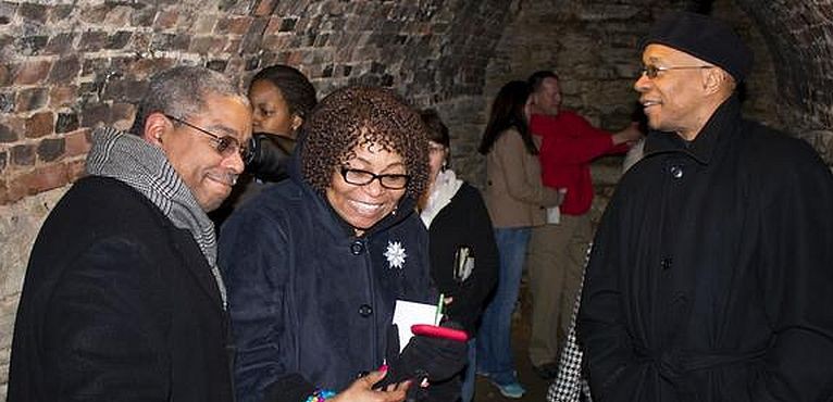 Photo by Louise Jett, Lewis and Clark Community College media specialist (2014). Tour guide and L&C instructor J. E. Robinson, left, discusses local history with Gwen Price and Jared Hennings, Black Student Association advisor, in the basement of the Enos Apartment Building in Alton, Feb. 28 2014, during an Underground Railroad Tour offered by Lewis and Clark Community College in honor of Black History Month. 