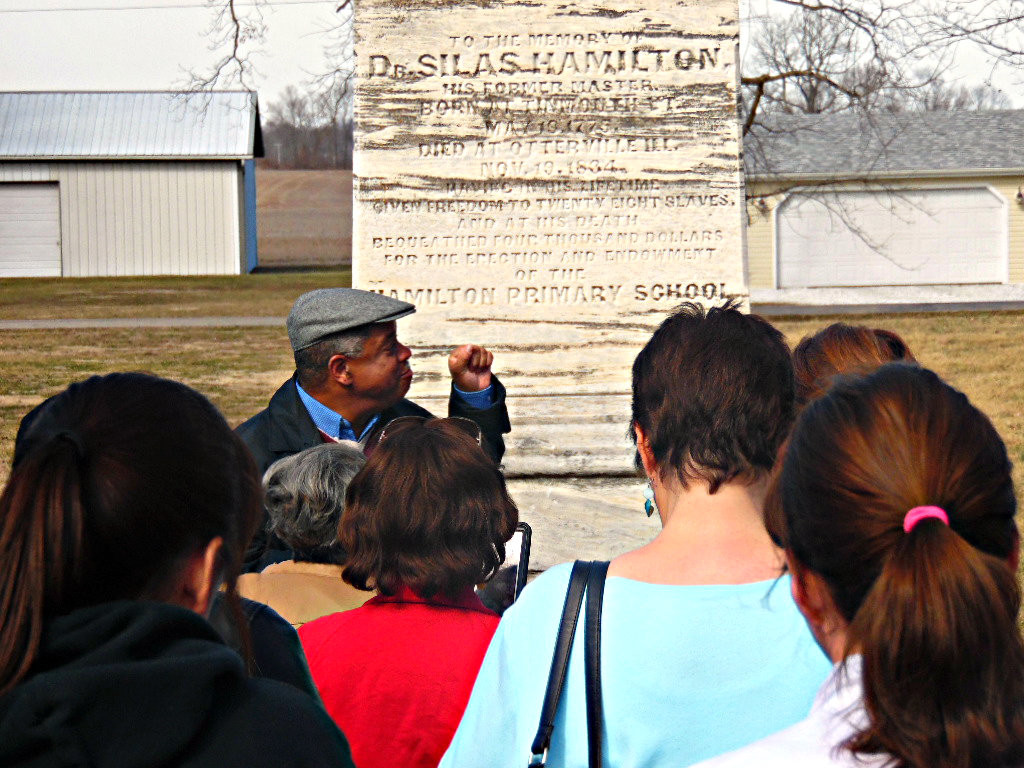 Tour director, J.E. Robinson, speaks to the group about Dr. Silas Hamilton’s life and one of his former slaves, George Washington. He also spoke about the history behind the Hamilton Primary School. Photo By: Krystie Morrison