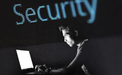 image of a man on his computer with the word security in blue behind him