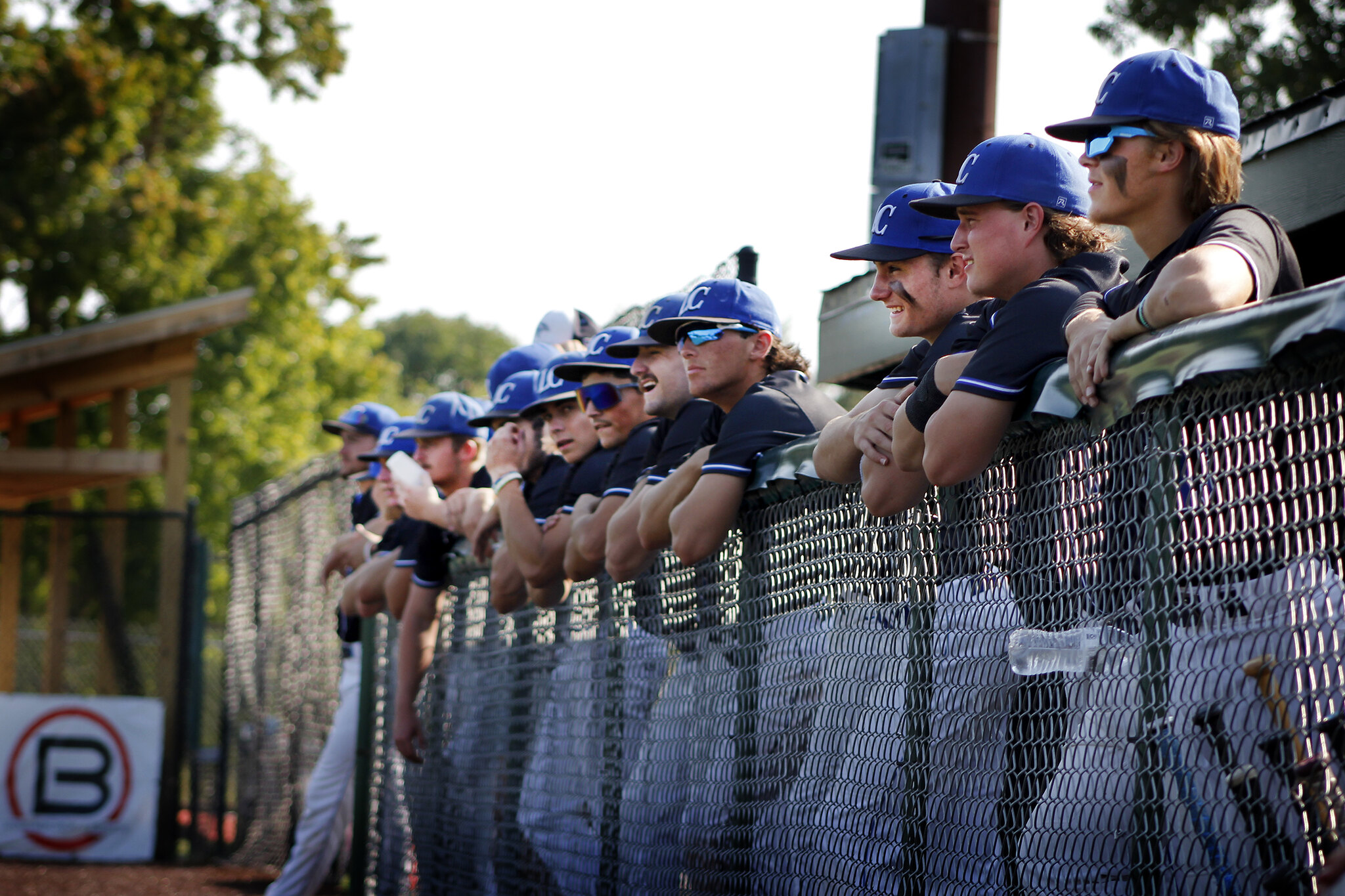 Line of baseball players waiting by a fence to play