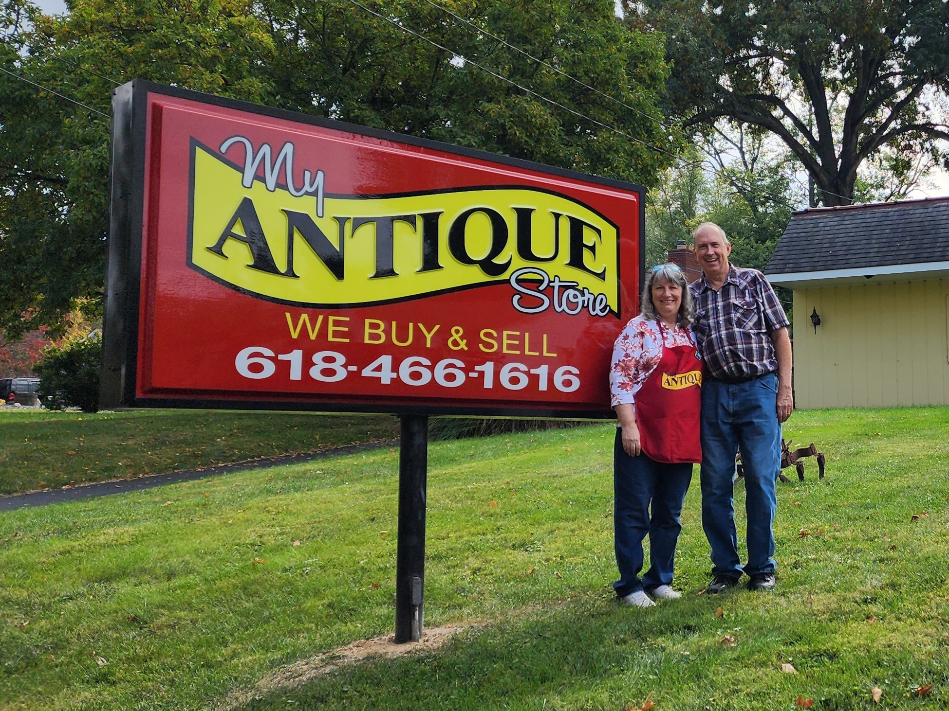 Owners stand beside my antique store sign