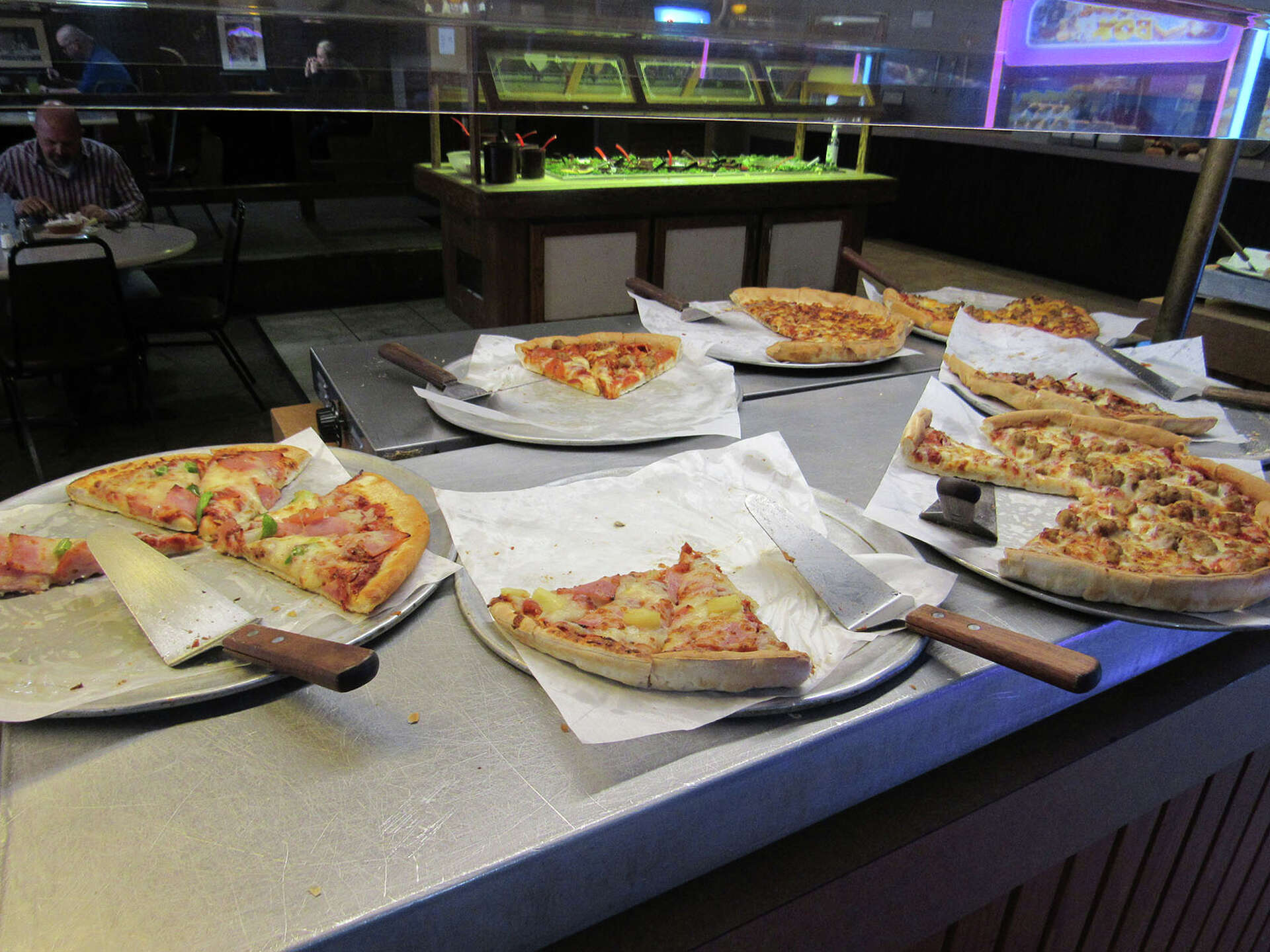 Pizza's sitting out on a table in a buffet area